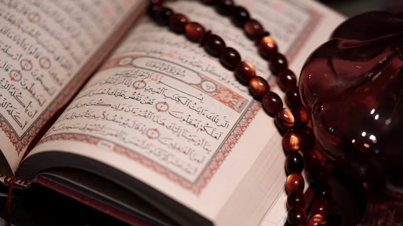 An open Quran with prayer beads, illustrating the study of Quran translation.